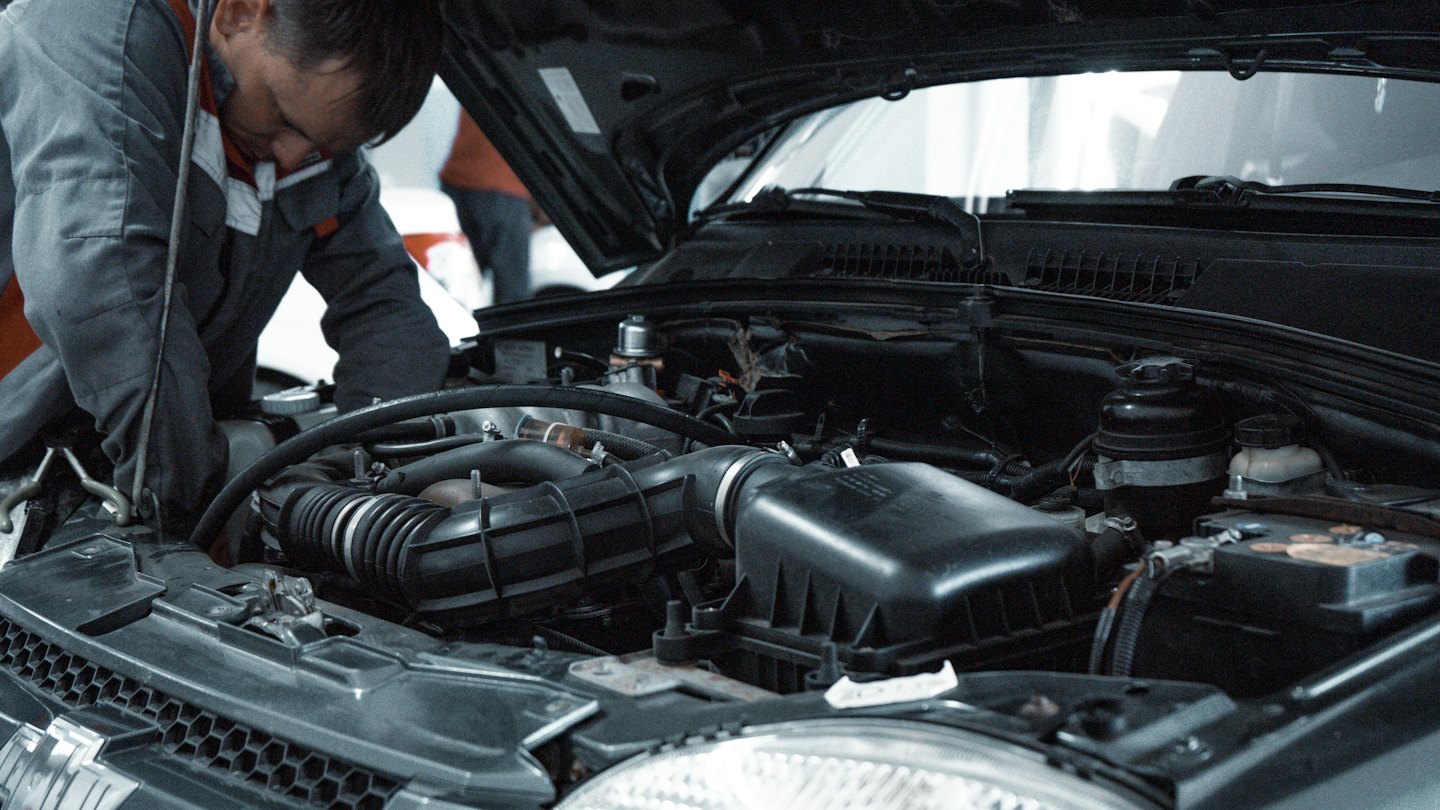 Mechanik pracuje na motore auta v autoservise.